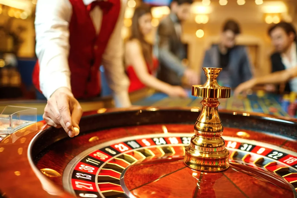 El crupier sostiene en la mano una bola de ruleta de casino.