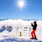 Kvinna skidåkare skidåkning i Zillertal Arena skidort i Tyrolen i Mayrhofen i Österrike i vinter Alperna. Flicka skidor i alpina berg med vit snö och blå himmel. Downhill kul på österrikiska snöiga backar.
