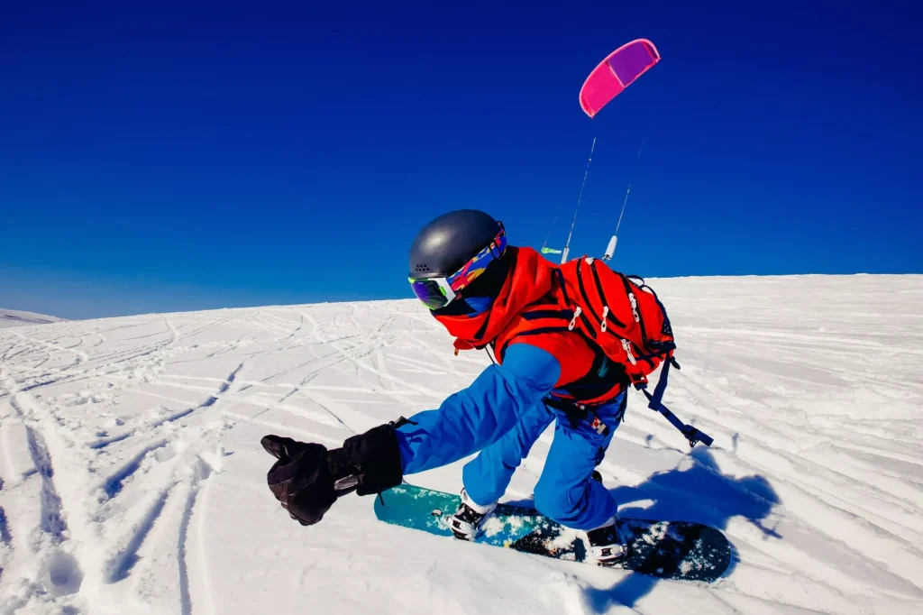 Snowboarder med kite på nysnø om vinteren på tundraen i Russland mot en klarblå himmel. Teriberka, Kolahalvøya, Russland. Konsept for vintersport med snowkite.