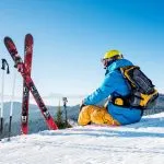 Vista posteriore di uno sciatore seduto in cima alla montagna vicino alla sua attrezzatura da sci che si rilassa godendo di belle montagne innevate vista persone che vivono divertimento ricreazione viaggio equitazione
