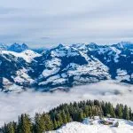 Vista aérea panorámica de un paisaje invernal en los Alpes austriacos por encima de las nubes bajas que cubren Kitzbuhel en Austria.