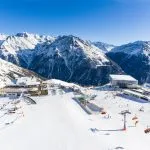Stazione sciistica nelle Alpi con impianto di risalita e persone che sciano in pista