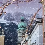 Tetti di Innsbruck con montagne sullo sfondo e luci di Natale in primo piano in una serata invernale di neve